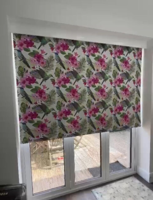 Electric roller blind for bifold doors in Docklands, East London lowered partway, here in a bright floral pattern