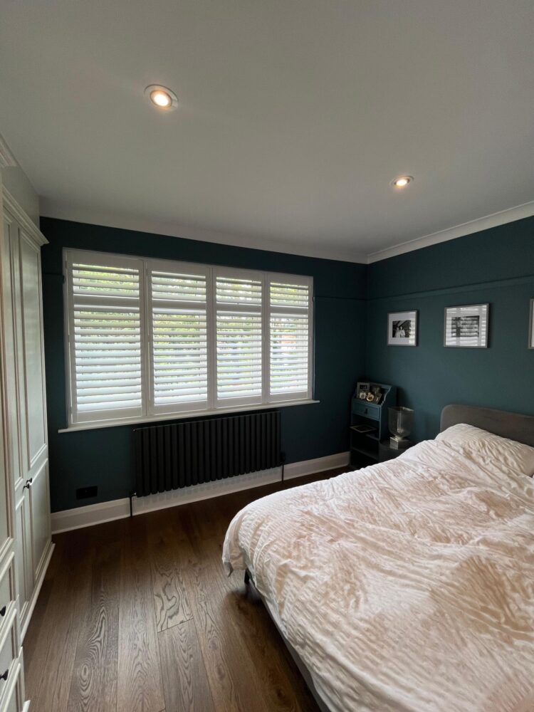 wooden plantation shutter blinds and wooden floor help with allergies in this North London Bedroom